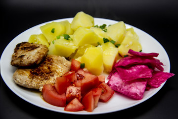 Mini steaks of meat with potatoes, tomatoes and pickled cabbage name Pelyustka on white plate. Healthy breakfast with meat, boiled potatoes, tomatoes and red pickled cabbage. Delicious meal for lunch