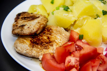 Mini steaks of meat with potatoes, tomatoes and pickled cabbage name Pelyustka on white plate. Healthy breakfast with meat, boiled potatoes, tomatoes and red pickled cabbage. Delicious meal for lunch