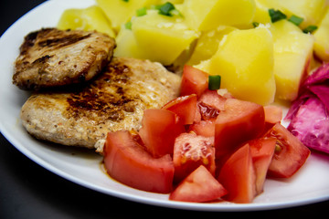 Mini steaks of meat with potatoes, tomatoes and pickled cabbage name Pelyustka on white plate. Healthy breakfast with meat, boiled potatoes, tomatoes and red pickled cabbage. Delicious meal for lunch