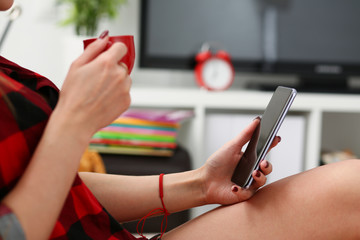 young blond pretty woman drinking coffe and look at laptop in morning sit on sofa