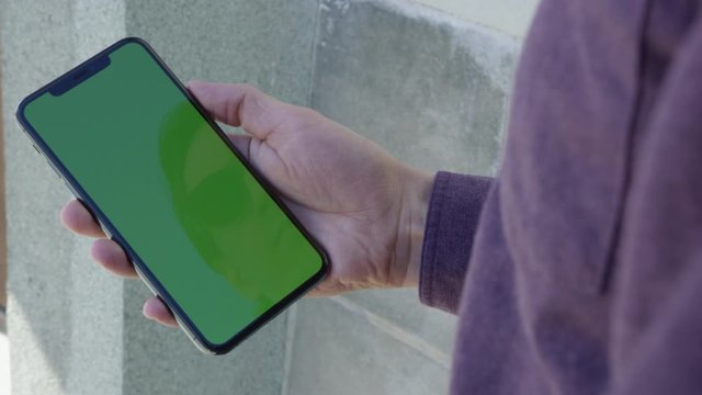 Male hand tapping and scrolling on mobile phone with chroma key green screen and reflection of face