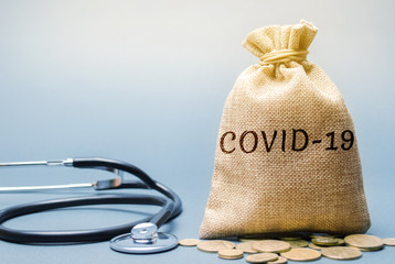 Money bag with the word Covid-19 and a stethoscope. Coronavirus pandemic infection. Healthcare,...