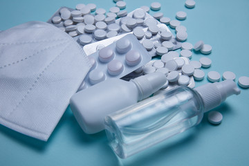 Medical face mask, sanitizer and pills on a blue background
