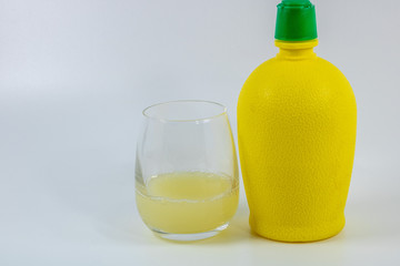 Bidon de citron jaune pressé et un verre de jus de citron sur fond blanc