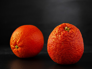 Two juicy ripe citruses - Sicilian red orange located on a stone black background. Close-up