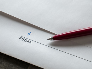 Close-up of a pen and a sheet of paper showing the word SIGNATURE in Spanish