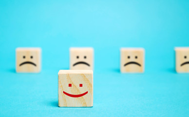 One block with a positive face stands out from the rest of the negative emotions. Concept of good rating, review and feedback. Satisfied customers. Selective focus