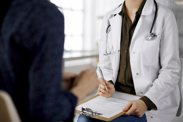 Doctor and patient discussing current health examination while sitting in clinic. Perfect medical...