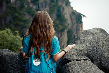 Naklejka premium Girl with a long hair are looking to the mountains back view 