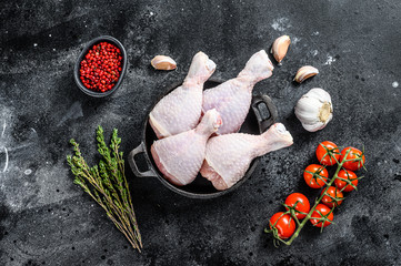 Raw chicken drumsticks , legs with herbs and spices in a pan. Organic poultry meat. Black background. Top view