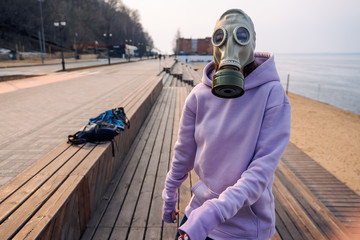 a girl in a gas mask walks around the city, the beach