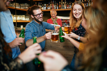 Group of friends drinking beer, chatting and having good time at pub. Night out.