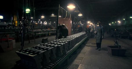 Metallurgical plant workers work on the conveyor of an engine factory - Powered by Adobe