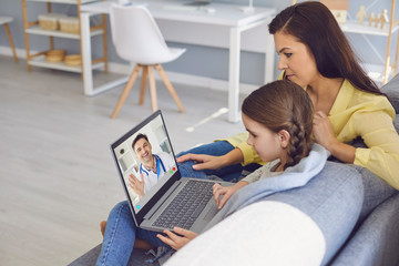 Online doctor. A male doctor online consults a diagnosis of symptoms to a mother and daughter through video chat using a laptop.