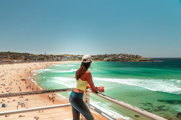 Woman at Bondi Beach, Sydney, Australia. Girl in work out gear looking at view of the ocean, sun,...