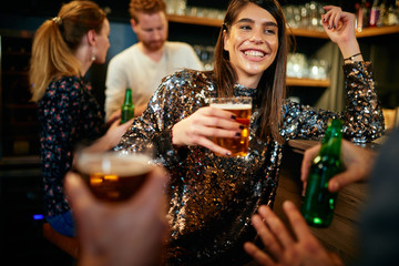 Group of friends drinking beer, chatting and having good time at pub. Night out.