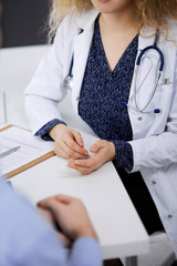 Female doctor and male patient discussing current health examination while sitting in clinic,...