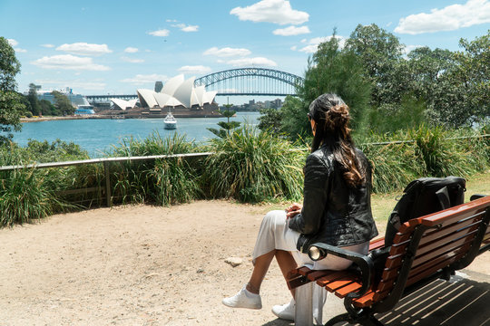 Woman With Sydney Opera House & Harbour Bridge. Tourist Looking At Attraction, With River Water. Blue Sky Tourism Shot. Boats On River. Famous Landmark.