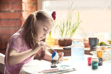 a 6 year old girl paints on an Easter egg