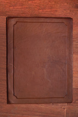 Fototapeta premium Antique brown aged leather cover with different spots on a wooden brown background