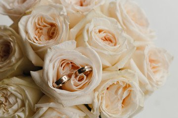 Gold wedding rings lying on the bouquet of the roses