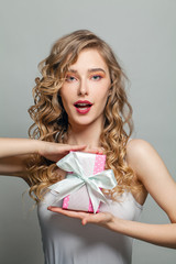 Happy woman holding pink gift with white silky ribbon