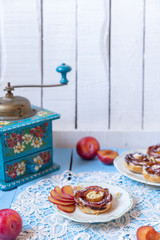 gebackene Blätterteigrosen mit Pflaumen und Puderzucker auf  hellen blauen Brettern aus Holz im nostalgischen Stil wie früher bei Oma