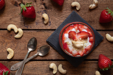 Püree mit Erdbeeren und Cashewjoghurt gehackt und gestückelt als süße Nachspeise auf dunklen Brettern aus Holz in einem rustikalen Stil