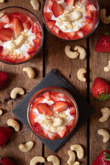 Püree mit Erdbeeren und Cashewjoghurt gehackt und gestückelt als süße Nachspeise auf dunklen Brettern aus Holz in einem rustikalen Stil