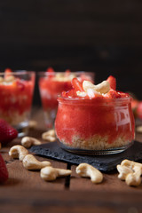 Püree mit Erdbeeren und Cashewjoghurt gehackt und gestückelt als süße Nachspeise auf dunklen Brettern aus Holz in einem rustikalen Stil