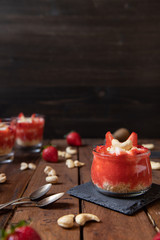 Püree mit Erdbeeren und Cashewjoghurt gehackt und gestückelt als süße Nachspeise auf dunklen Brettern aus Holz in einem rustikalen Stil