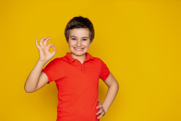 Portrait of a pretty teenager 11-12 years old in red polo on a yellow background. various emotions and gestures with hands.