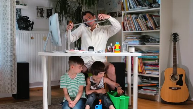 Home office in the family. A multi-tasking man ties a tie. Son steals a sandwich from the table. Adaptation to home isolation. Stress in the home office COVID-19.