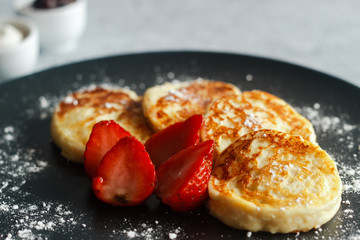 Tasty cheese pancakes with strawberries, sour cream and cherry jam. Cheese pancakes on a plate