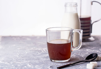 Obraz na płótnie Canvas Coffee with milk in a glass cup, spoon, sugar, custard, a bottle of milk on a glass background.