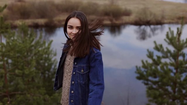 Happy woman walking in nature. Young hipster female spining around with arms to side while strolling hill along river