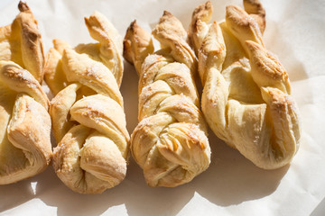 fresh pastries from puff pastry in the form of braided braids lie on parchment paper