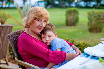  little boy sleeping near his grandmother in outside.  horizontal