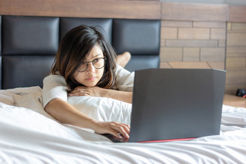 young business woman using laptop on bed while working from home during covid -19 crisis.