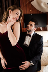 handsome, elegant man touching seductive, flirty woman in plane