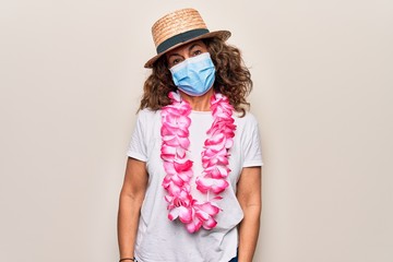 Middle age tourist woman wearing coronavirus protection mask and summer hat on vacation with a happy and cool smile on face. Lucky person.
