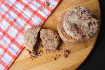 Homemade Chocolate chip sugar cookies with milk bottle on rustic wooden board with ingredients like, chocolates, all purpose flour, eggs, kitchen napkin, whisk and measuring spoons. copy space.