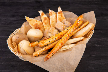Bread basket with black and white bread, tortillas and crisp sticks