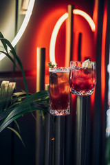 bright cocktail in a beautiful glass neon lighting and plants background 