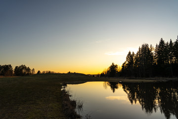 Obraz premium Sunset over a calm forest lake with gorgeous colors.