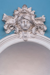 A human sculpture hangs on a blue wall above the arch, the sad face of a man is depicted in plaster