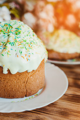 Beautiful glazed easter cake decorated with colored powder on wooden background. Happy Easter Holidays. Vertical photo