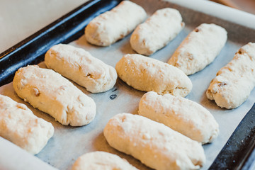 Raw curd buns with raisins lie on a baking sheet. Raw dough. Unbaked buns. Selective focus