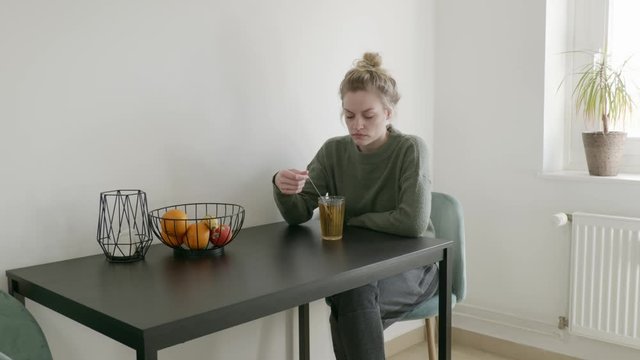 Sad woman sits home alone drinking tea