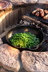 String beans in a pan. Vegetables and meat are fried over an open fire. Family life outside the city. Lifestyle